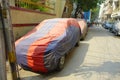 Close up of a car parked covered with a huge fabric with color red and blue, near of the Laxminarayan Temple, is a