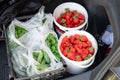 Close-up car trunk with fresh ripe organic vegetables and berries bought on farmers market. Red juicy sweet strawberries ,