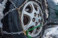 Close-up of a car wheel with snow chains. The fenders of the car are forgotten by the muddy snow. Selective focus. The