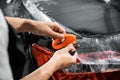 Close-up of car wrapping specialist hand straightening wrapping transparent film for protection with a film cutter to cut a film