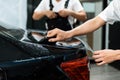 Close-up of car wrapping specialist hand straightening wrapping transparent film for protection with a squeegee.