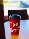 Close up on a cardboard coffee cup with Tim Hortons logo in one of their restaurants.