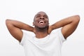 Close up carefree african american man laughing with hands behind head against white background