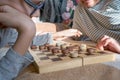 Close-up of a caring middle-aged grandmother playing checkers with a child, a boy, while lying on the bed. Happy family Royalty Free Stock Photo