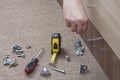 Close-up of carpenter hand tightens fixing screw, using key furn