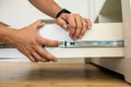 Close up of carpenter hands installing wooden drawer on sliding skids in contemporary cupboard cabinet Royalty Free Stock Photo