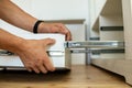 Close up of carpenter hands installing wooden drawer on sliding skids in contemporary cupboard cabinet Royalty Free Stock Photo