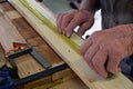 Close up of carpenter hands measuring a wooden plank