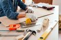 Close-up carpenter hands wearing work gloves draw the cutting line with a pencil on a wooden board. Construction industry, Royalty Free Stock Photo