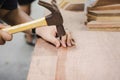 Close up of a Carpenter hitting a nail into a wooden board using a metal hammer. Royalty Free Stock Photo