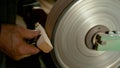 CLOSE UP: Carpenter holds a piece of wood against a wheel covered with sandpaper Royalty Free Stock Photo