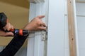 Close-up carpenter process of hands screwing hinge on a door with screwdriver Royalty Free Stock Photo
