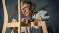 Close Up of a Carpenter Putting on Glasses, Looking at a Blueprint and Starting to Assemble a Wooden