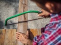 close up of Carpenter sawing a board with a hand wood saw. profession, carpentry, woodwork and people concept. Royalty Free Stock Photo