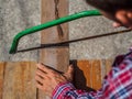 close up of Carpenter sawing a board with a hand wood saw. profession, carpentry, woodwork and people concept. Royalty Free Stock Photo