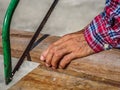 close up of Carpenter sawing a board with a hand wood saw. profession, carpentry, woodwork and people concept. Royalty Free Stock Photo