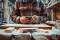 A close-up of a carpenter using his phone in a rustic workshop, highlighting the integration of technology in