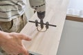 Close-up of carpenters hand using professional woodworking electric tools when working with wood. Male carving hole in wooden