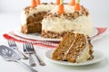 A close up of a carrot cake with cream cheese frosting and a piece of cake in front ready for eating. Royalty Free Stock Photo