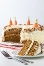 A close up of a carrot cake with cream cheese frosting and a slice of cake in front ready for eating. Royalty Free Stock Photo