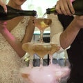 Close up of a cascade champagne fountain made by groom and bride at banquet background. Newly married pour sparkling