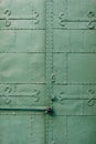 Close-up of the castle-closed green gate with patterns, squares and rivets.