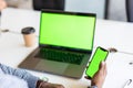 Close up of casual man or freelancer working on laptop computer and holding mobile smart phone with reflection on blank screen, Royalty Free Stock Photo