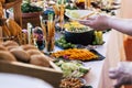 Close up of catering service table full of food and people serving and taking on dishes. Concept of holiday event like wedding or Royalty Free Stock Photo