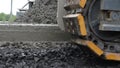 Close-up of caterpillar tread of crawler slowly moving along edge of concrete roadbed