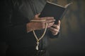 Close up of Catholic priest holding Bible and rosary reading prayer Royalty Free Stock Photo
