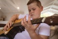 Close up of caucasian boy playing guitar sitting on the couch at home Royalty Free Stock Photo