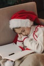 Close-up Caucasian child, lovely baby girl in Santa hat, makes cherished wish and cute presents, surrounded by Christmas Royalty Free Stock Photo