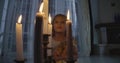 Close-up of Caucasian girl`s face behind candles. Weird child holding doll and looking around. Scare, fear, strangeness.