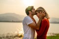 Close up Caucasian man kiss on forehead of beautiful woman with sunset light near lake and look romantic for couple love stay Royalty Free Stock Photo