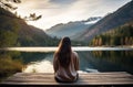 Woman sitting by mountain lake at dusk