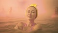 Close up caucasian woman in a swim in hot saline mineral water bath at a traditional spa outdoor with soft magic pink Royalty Free Stock Photo