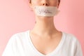 Close up of caucasian woman& x27;s face with her mouth taped shut. Tape has the inscription Shhh. Pink background Royalty Free Stock Photo