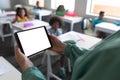 Close-up caucasian young female teacher using digital tablet with multiracial students in background Royalty Free Stock Photo