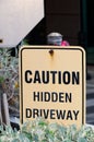 Close up on a `Caution Hidden Driveway` sign along the driveway of a building parking garage