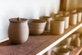 Close-up on Ceramic Cup with Lid on wooden display shelf for hand crafted Ceramic such as bowls, plates and cups. Creative worksho