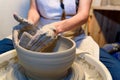 close up of ceramist woman hands working and shaping clay on the lathe or potter's wheel inside a pottery workshop