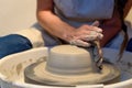 close up of ceramist woman hands working and shaping clay on the lathe or potter's wheel inside a pottery workshop