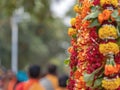 Close-up of a ceremonial procession with a pole decorated with a bunch of colorful flowers held by devotees