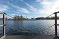 Pier at River - Chain Fencing Close Up - Under a Blue Cloudy Sky - Industry in the Background Royalty Free Stock Photo