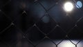 Close up of chain link fence on dark blurred background with shining lamp. Video. Metal lattice inside the building Royalty Free Stock Photo