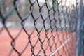 Close-up on a chain-link fence with a tennis court in the background. Royalty Free Stock Photo