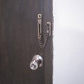 chain lock and doorknob on brown door Royalty Free Stock Photo