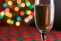 Close up of champagne glass with selective focus, festive abstract background with beautiful bokeh of colorful lights and copy