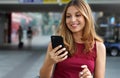 Close-up of charming beautiful business woman smile in casual style using smartphone walking in train or metro station