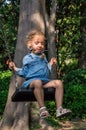 Close up. Charming girl in a blue dress riding on a swing Royalty Free Stock Photo